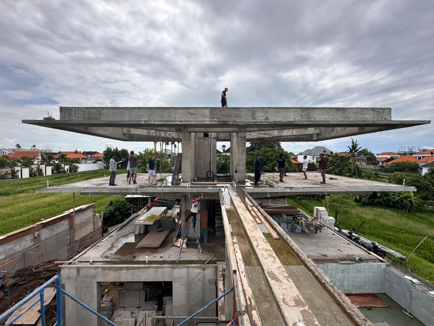 Workers stand atop the cantilevered concrete frame during construction of this Sumbawa villa.